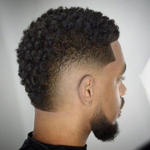 A black man with a temp fade hairstyle with twists and a black short beard.