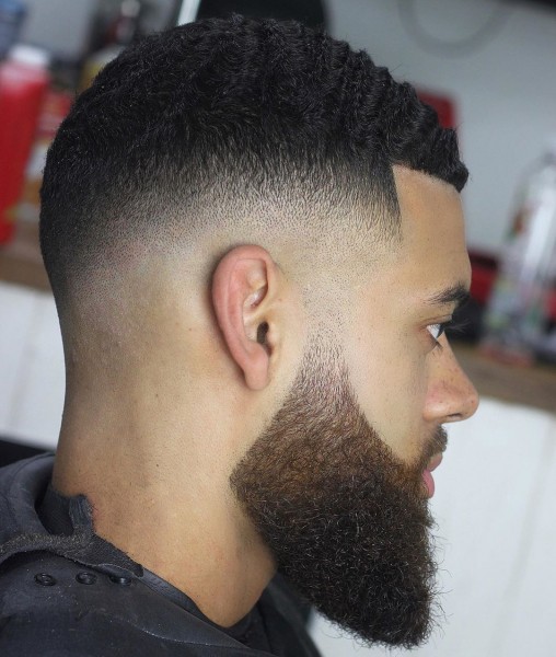 The man with a temp fade hairstyle with a beard a wavy hair.