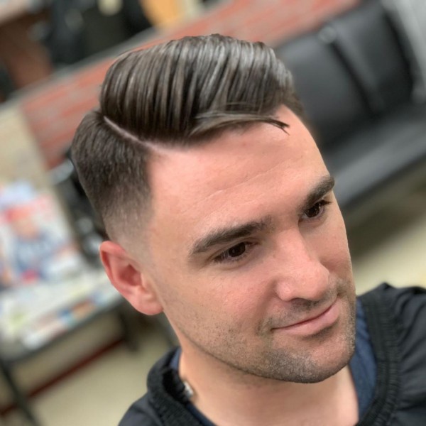 A handsome man with a temple fade and comb over.