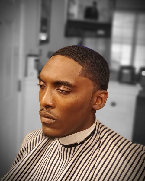 A black man with a temple fade hairstyle and short wavy hair.