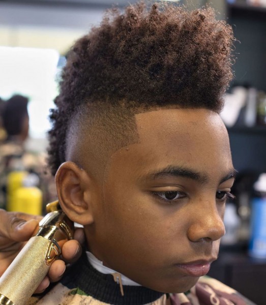 Young black boy with a Temple Fade with a Mohawk haircut.