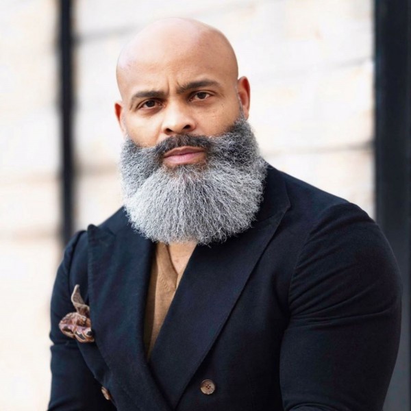A shaved head style with a long beard.