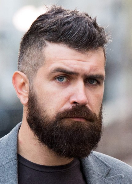 A brushed up haircut with short sides and full beard.