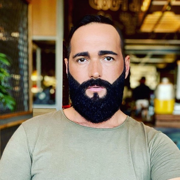 A low haircut with a full beard style.