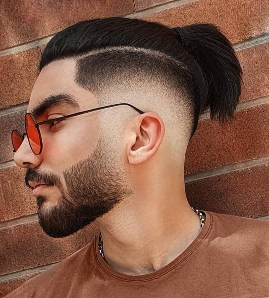 A low faded male haircut with a bun.