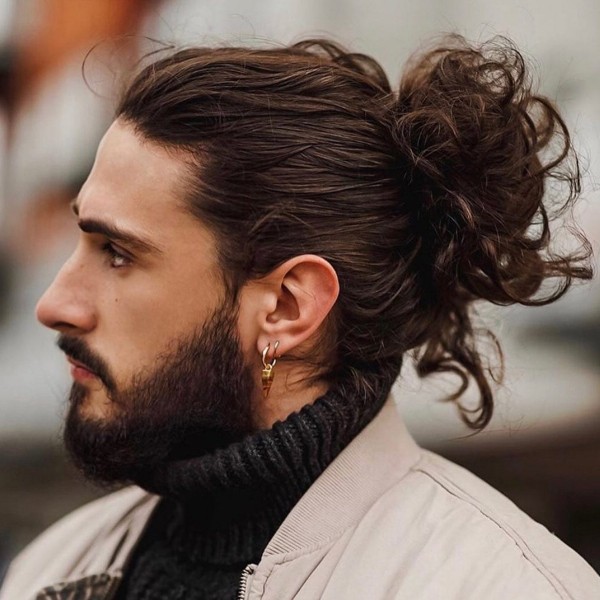 A wavy male hairstyle with a bun.